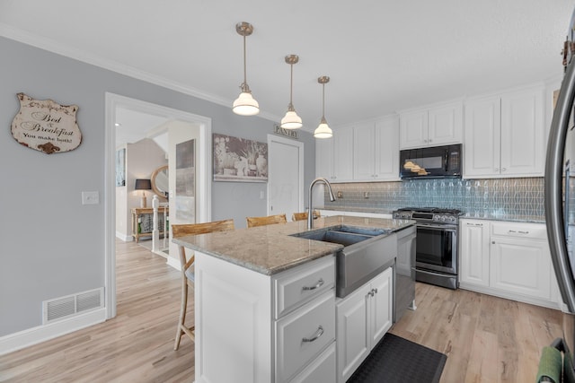 kitchen with a kitchen island with sink, white cabinetry, and stainless steel gas range oven