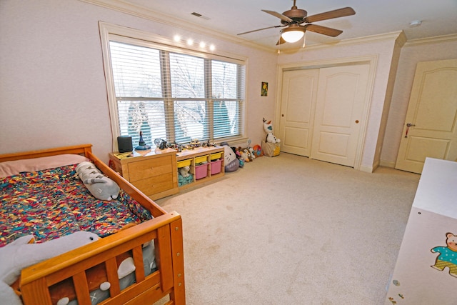 carpeted bedroom featuring ceiling fan, a closet, and crown molding