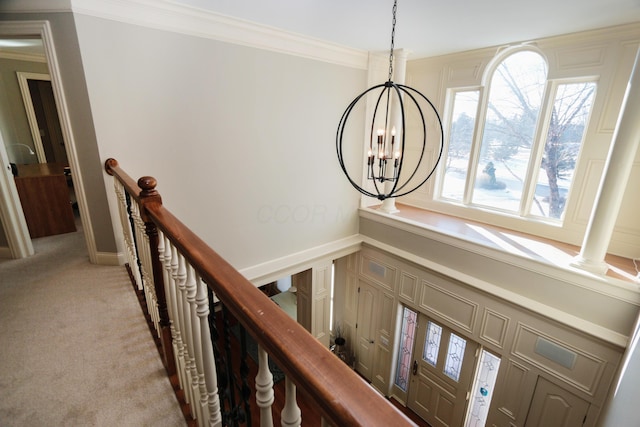 carpeted entryway featuring a notable chandelier and ornamental molding