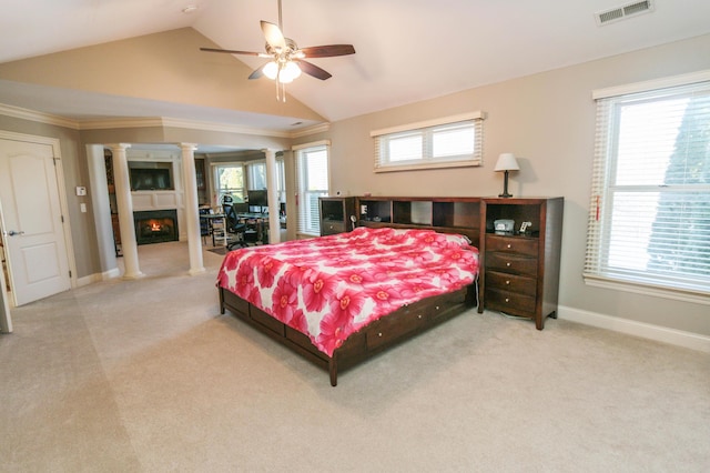 bedroom featuring light carpet, ornate columns, ornamental molding, vaulted ceiling, and ceiling fan