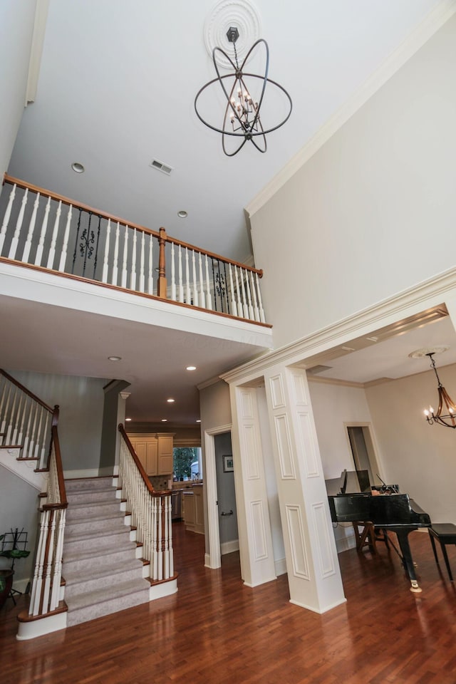 stairway with ornamental molding, a chandelier, and hardwood / wood-style floors