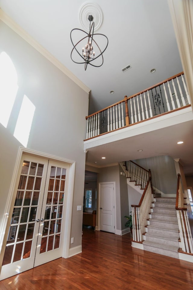 stairs with french doors, a towering ceiling, and crown molding