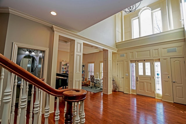 entrance foyer with hardwood / wood-style flooring, a high ceiling, and ornamental molding