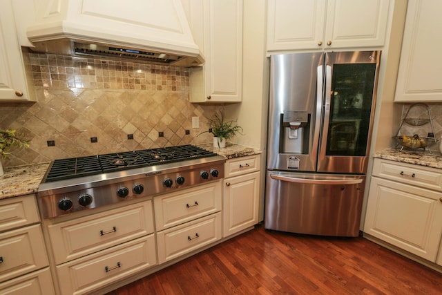 kitchen featuring appliances with stainless steel finishes, custom exhaust hood, tasteful backsplash, and light stone countertops