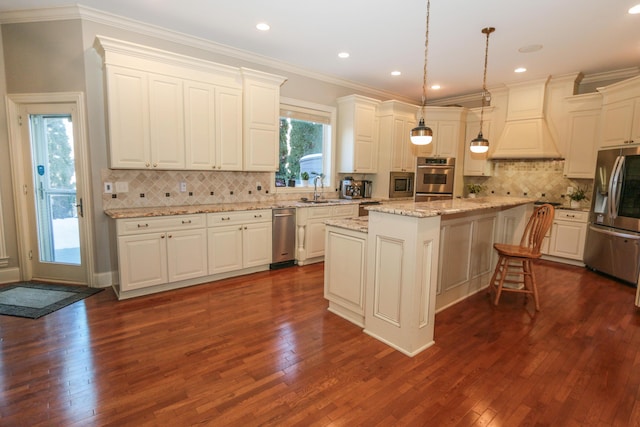 kitchen with custom exhaust hood, stainless steel fridge, hanging light fixtures, a kitchen island, and white cabinets