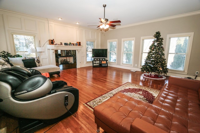 living room with ceiling fan, wood-type flooring, a high end fireplace, and crown molding