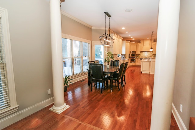 dining room featuring decorative columns, dark hardwood / wood-style flooring, and ornamental molding