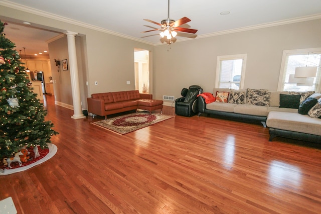 living room with hardwood / wood-style flooring, crown molding, and ornate columns