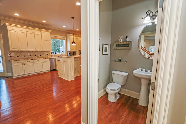 bathroom with toilet, decorative backsplash, hardwood / wood-style flooring, and sink