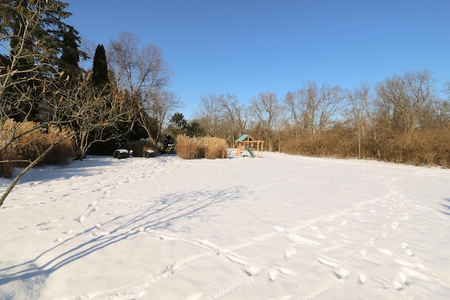 yard covered in snow featuring a playground