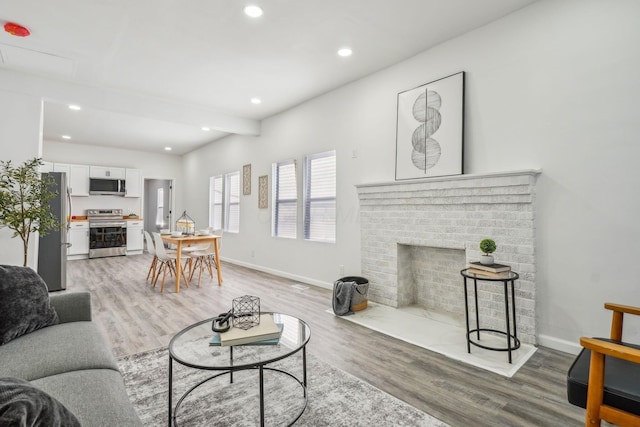 living room featuring light wood-type flooring and a brick fireplace