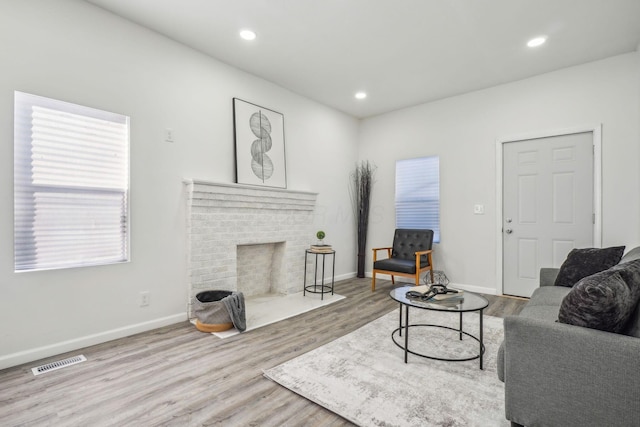 living room featuring light hardwood / wood-style floors and a brick fireplace