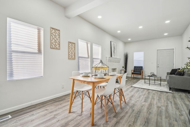 dining space with light hardwood / wood-style floors and beamed ceiling