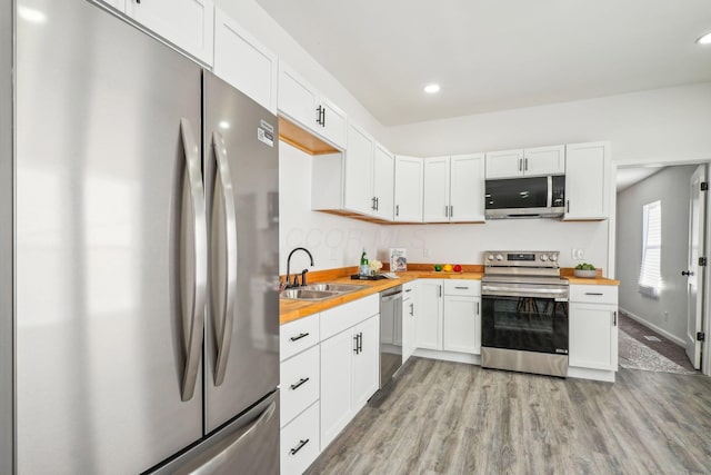 kitchen with white cabinets, appliances with stainless steel finishes, wood counters, sink, and light wood-type flooring