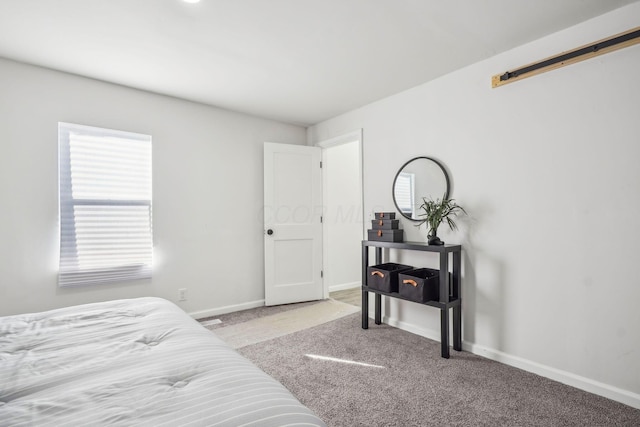 carpeted bedroom featuring multiple windows and a barn door