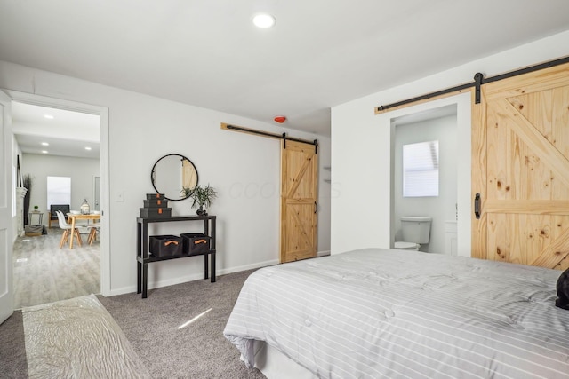 bedroom with carpet, ensuite bathroom, and a barn door