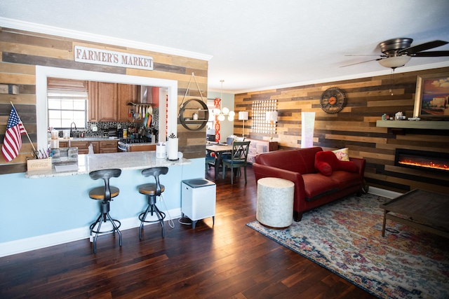 living room with wooden walls, dark hardwood / wood-style flooring, sink, and crown molding