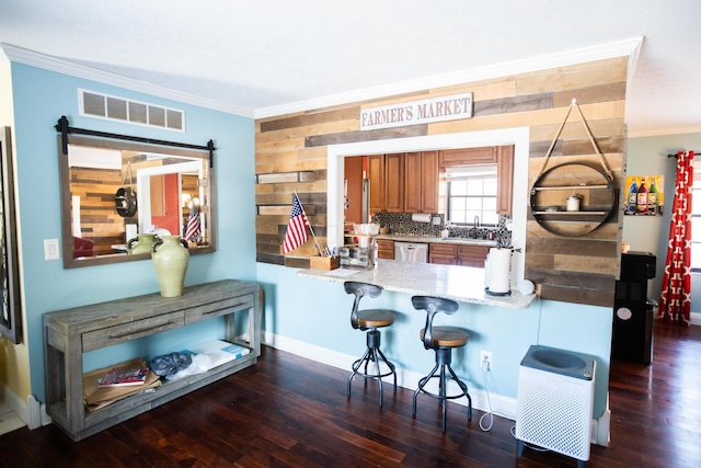 kitchen featuring a kitchen breakfast bar, ornamental molding, stainless steel dishwasher, and sink