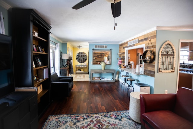 living room featuring ceiling fan, a textured ceiling, dark hardwood / wood-style floors, and crown molding