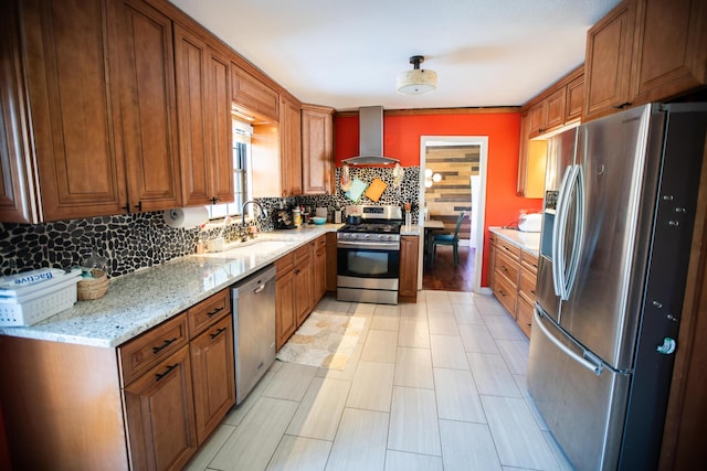 kitchen featuring light stone countertops, appliances with stainless steel finishes, wall chimney range hood, decorative backsplash, and sink