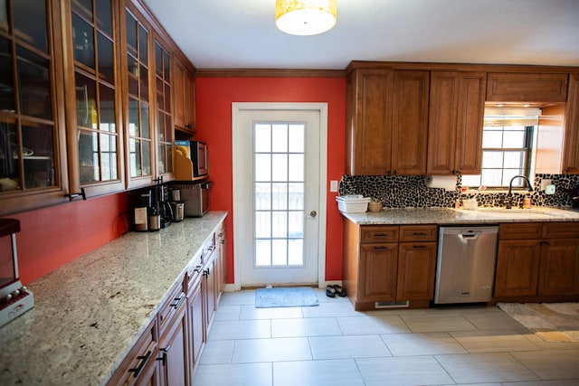 kitchen featuring decorative backsplash, sink, light stone counters, stainless steel dishwasher, and crown molding