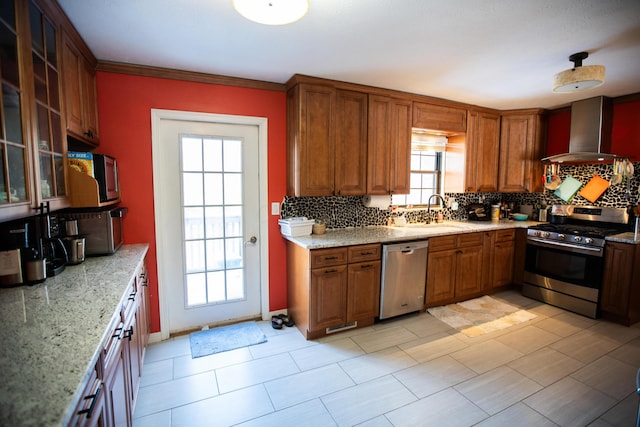 kitchen with light stone countertops, wall chimney range hood, appliances with stainless steel finishes, and a wealth of natural light