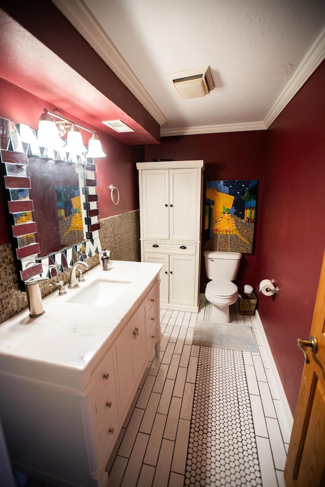 bathroom with toilet, crown molding, and vanity