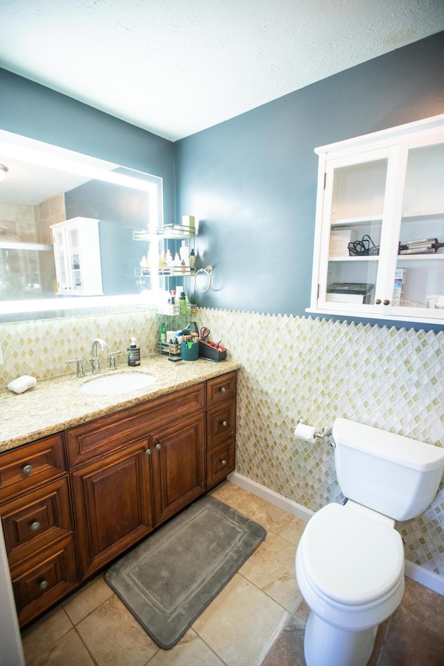 bathroom with toilet, tile patterned flooring, tile walls, and vanity