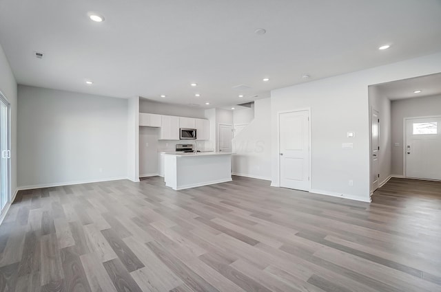 unfurnished living room featuring recessed lighting, light wood-type flooring, and baseboards