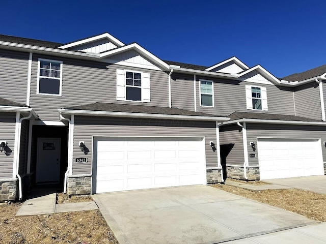 townhome / multi-family property with stone siding, an attached garage, and concrete driveway