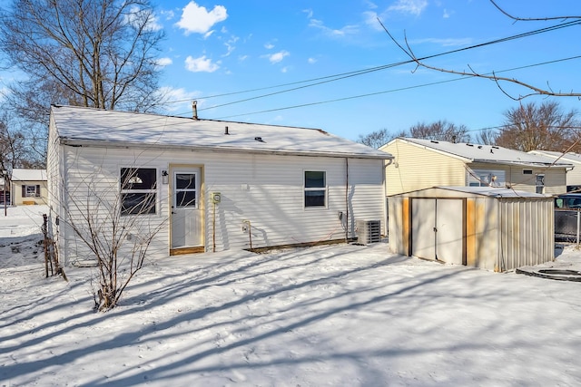 snow covered house with central air condition unit and an outdoor structure