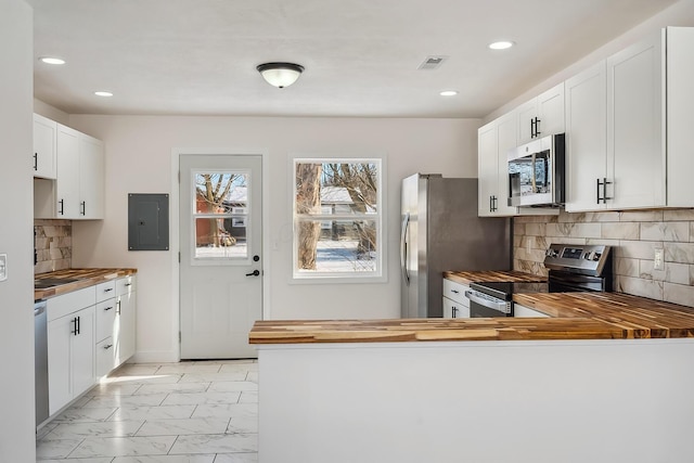 kitchen with white cabinetry, stainless steel appliances, wooden counters, and tasteful backsplash