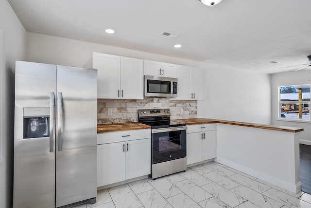 kitchen with backsplash, butcher block countertops, kitchen peninsula, white cabinetry, and appliances with stainless steel finishes