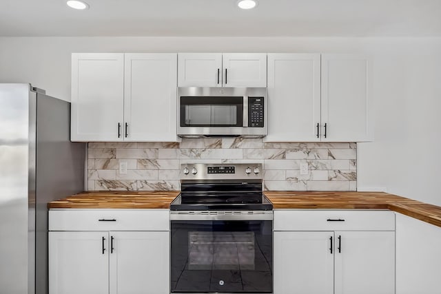 kitchen featuring butcher block counters, appliances with stainless steel finishes, decorative backsplash, and white cabinetry