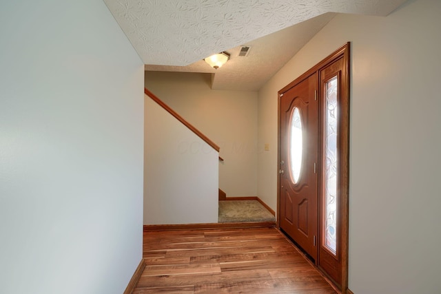 foyer featuring light wood-type flooring and a textured ceiling