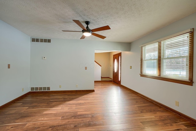 empty room with ceiling fan, a textured ceiling, and wood-type flooring