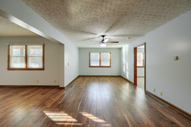 unfurnished room featuring plenty of natural light, a textured ceiling, and dark hardwood / wood-style floors