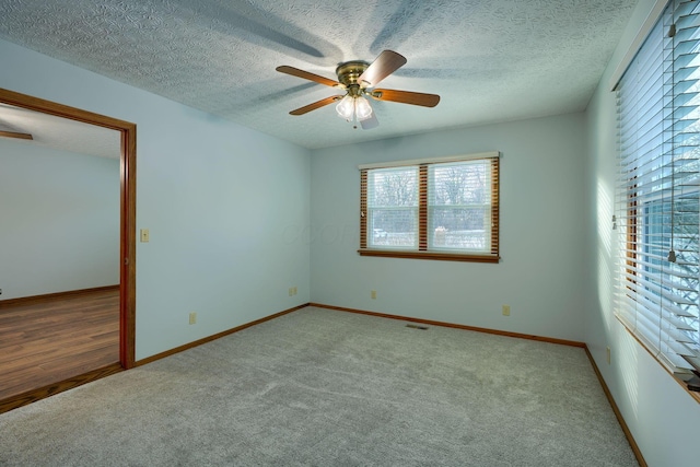 empty room featuring ceiling fan, carpet, and a textured ceiling