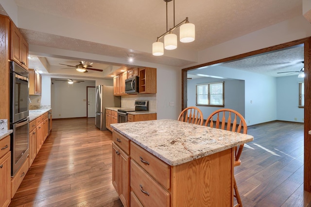 kitchen with a kitchen island, dark hardwood / wood-style flooring, decorative light fixtures, and appliances with stainless steel finishes