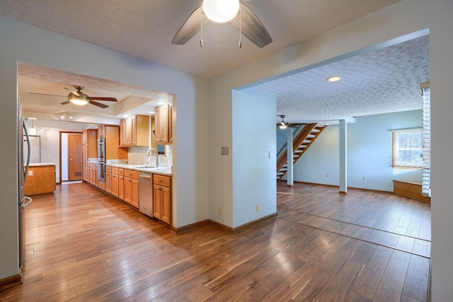 kitchen featuring sink, wood-type flooring, a textured ceiling, and appliances with stainless steel finishes