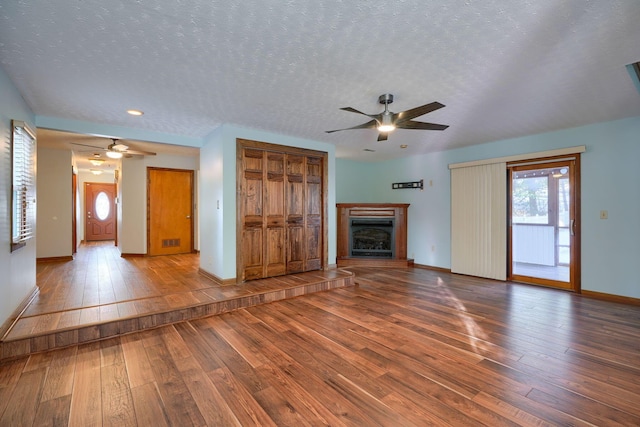 unfurnished living room featuring wood-type flooring, a textured ceiling, and ceiling fan