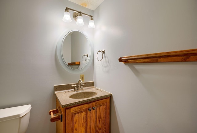 bathroom with a textured ceiling, toilet, and vanity