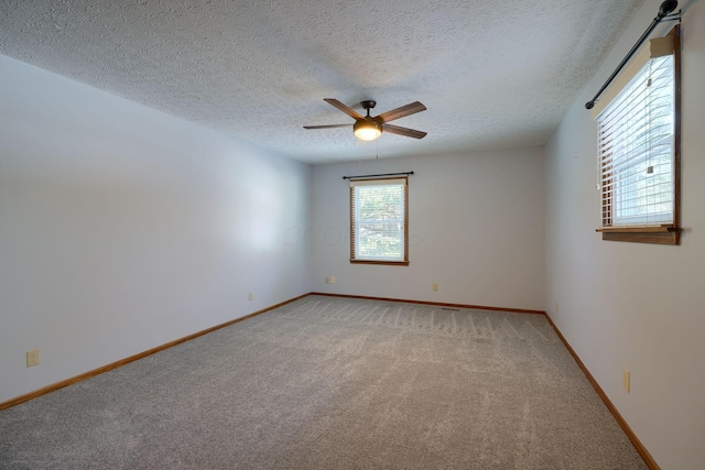 carpeted spare room featuring ceiling fan and a textured ceiling