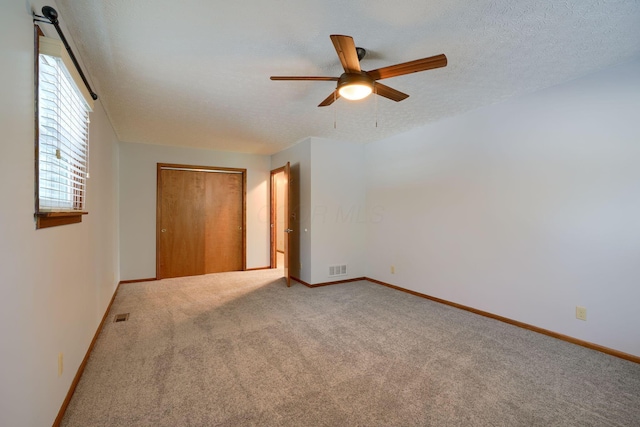 empty room with ceiling fan, carpet, and a textured ceiling