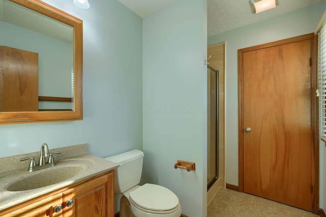 bathroom with a textured ceiling, toilet, a shower with shower door, and vanity