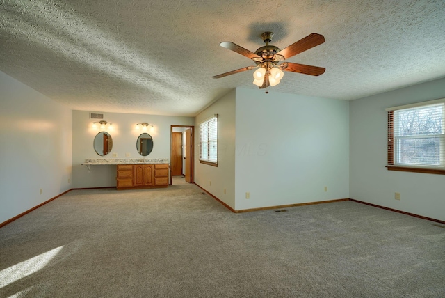 carpeted spare room featuring ceiling fan and a textured ceiling