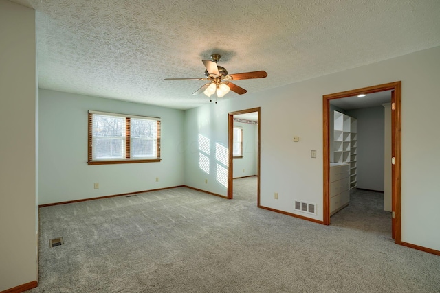 unfurnished room featuring ceiling fan, a textured ceiling, and light carpet