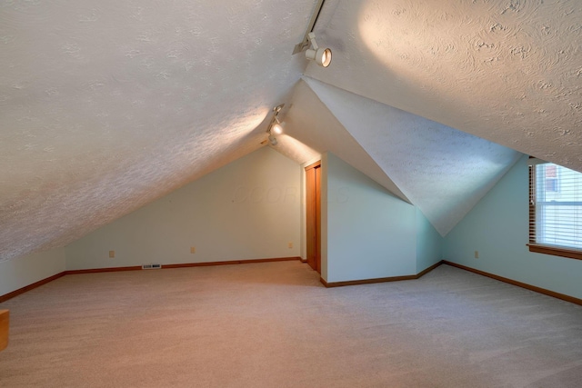 bonus room with light carpet, vaulted ceiling, and a textured ceiling