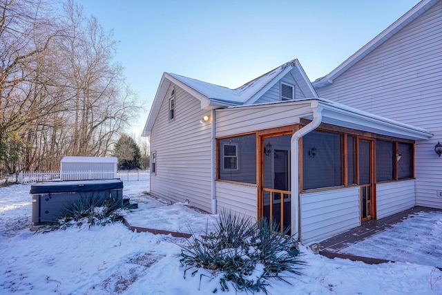 view of snow covered exterior with a hot tub and a sunroom