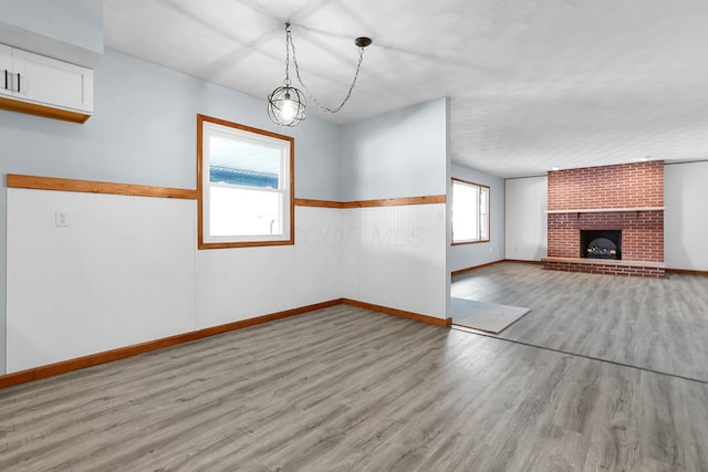 interior space with a brick fireplace, a wealth of natural light, and light wood-type flooring